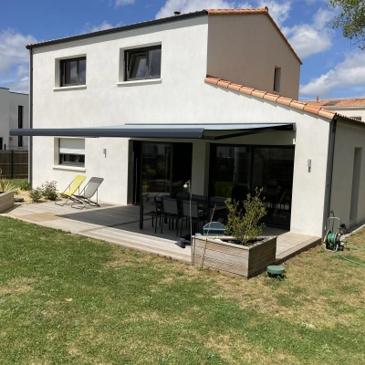 Vue d'une maison moderne avec un store banne ouvert couvrant une terrasse près de Pornic